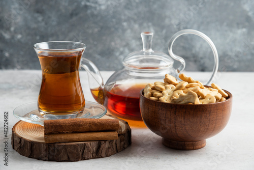 A glass cup of tea with wooden bowl full of crackers