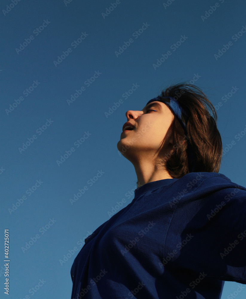 Happy cheerful joyful girl smiles against the blue sky and looks up. Happy cheerful joyful girl smiles against the blue sky and looks up.