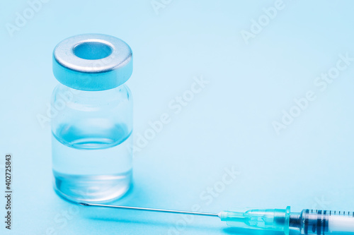 Syringe with a bottle to put a vaccine on a blue background.