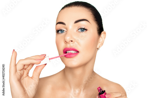 Portrait of a girl on a white background. Applies pink lipstick to lips..