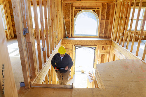 Building inspector looking at new home, holding tablet with hard hat