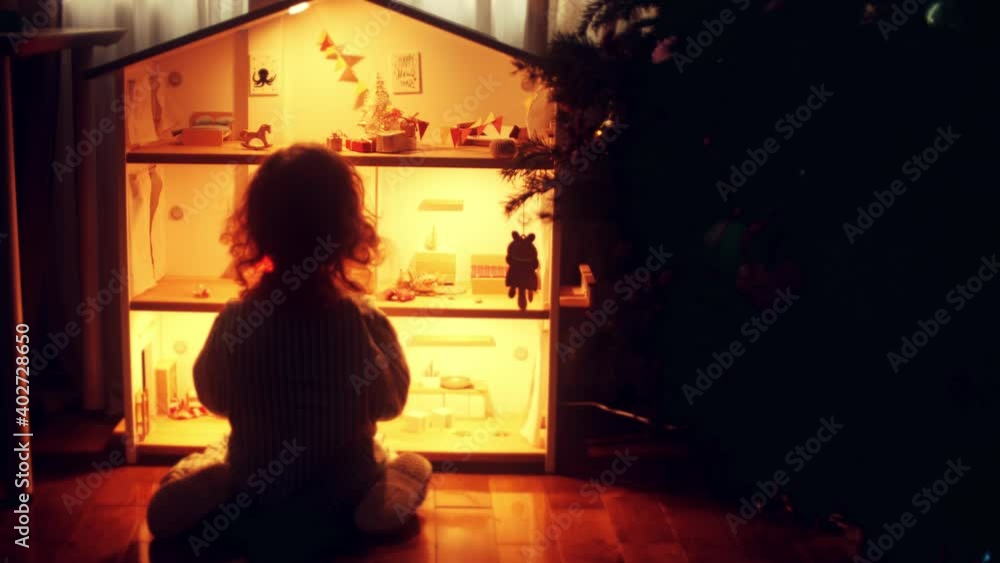 Little girl plays with a doll house at home at Christmas time Little girl plays with a doll house at home at Christmas time
