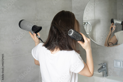 Girl dries her hair with a hairdryer