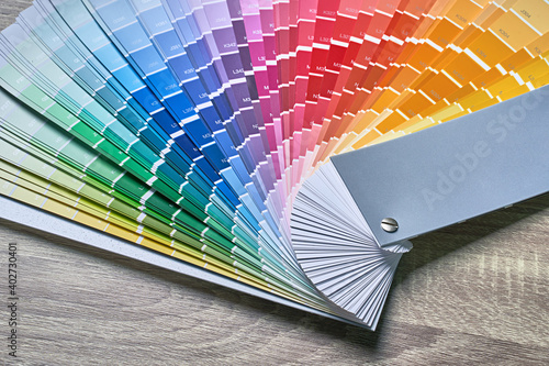 Color wheel palette for choosing paint tone. Various colors on wooden table background with copy space. Interior designer tool.