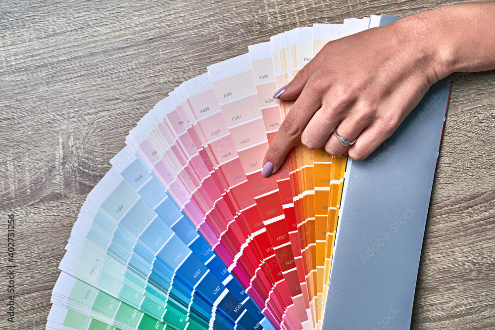 Color wheel for choosing paint tone. Hands of female interior designer working with palette for choosing colors. Creative process concept. Comparing options with matching hues.