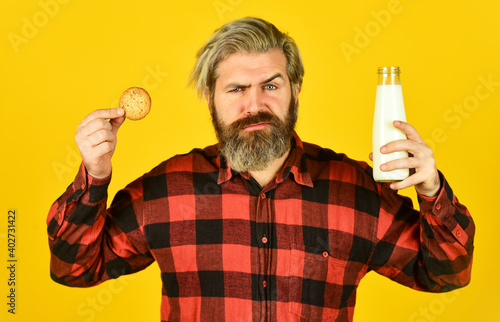 bearded man drink useful milk with pastry. Gingerbread cookie in a hot cup of milk. American famous snack. Cookies and cream in fresh milk glass. happy farmer eat cookie dessert
