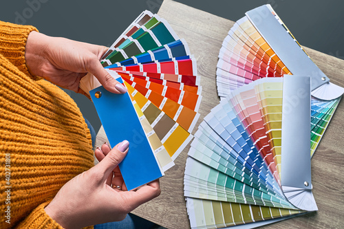 Obraz na płótnie Color wheel for choosing paint tone. Hands of female interior designer working with palette for choosing colors. Creative process concept. Comparing options with matching hues. w salonie