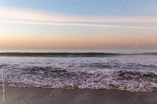 Waves washing ashore in colorful sunrise at Malibu Beach  California