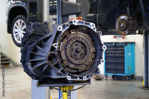 Automatic transmission (DSG) removed from vehicle for repair. In the background, the interior of a car service is blurred.  