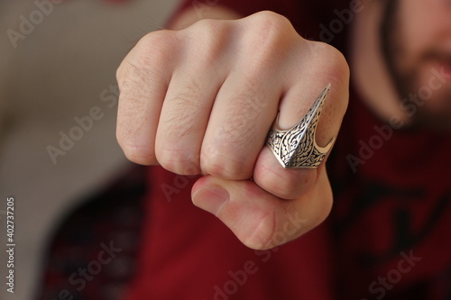 Young man showing punch.  Embroidered silver ring on finger. Thumb Ring in Traditional photo