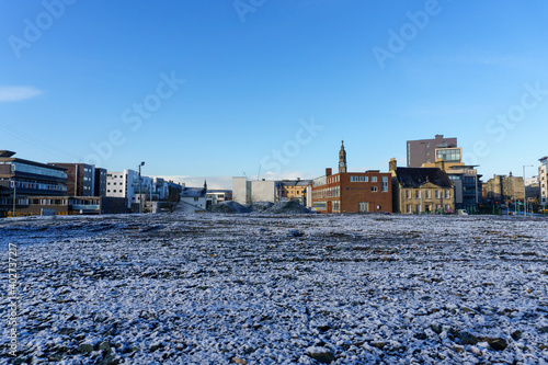 Low view of ice covered ground and city buildings in the background