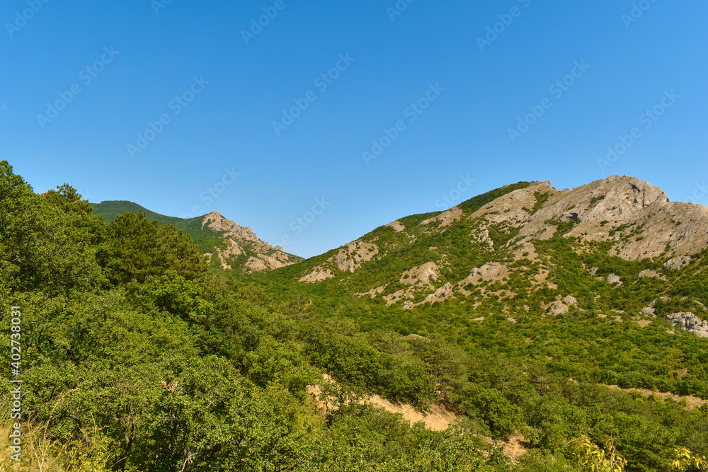 Green peaks of hills and mountains against a cloudless sky in summer