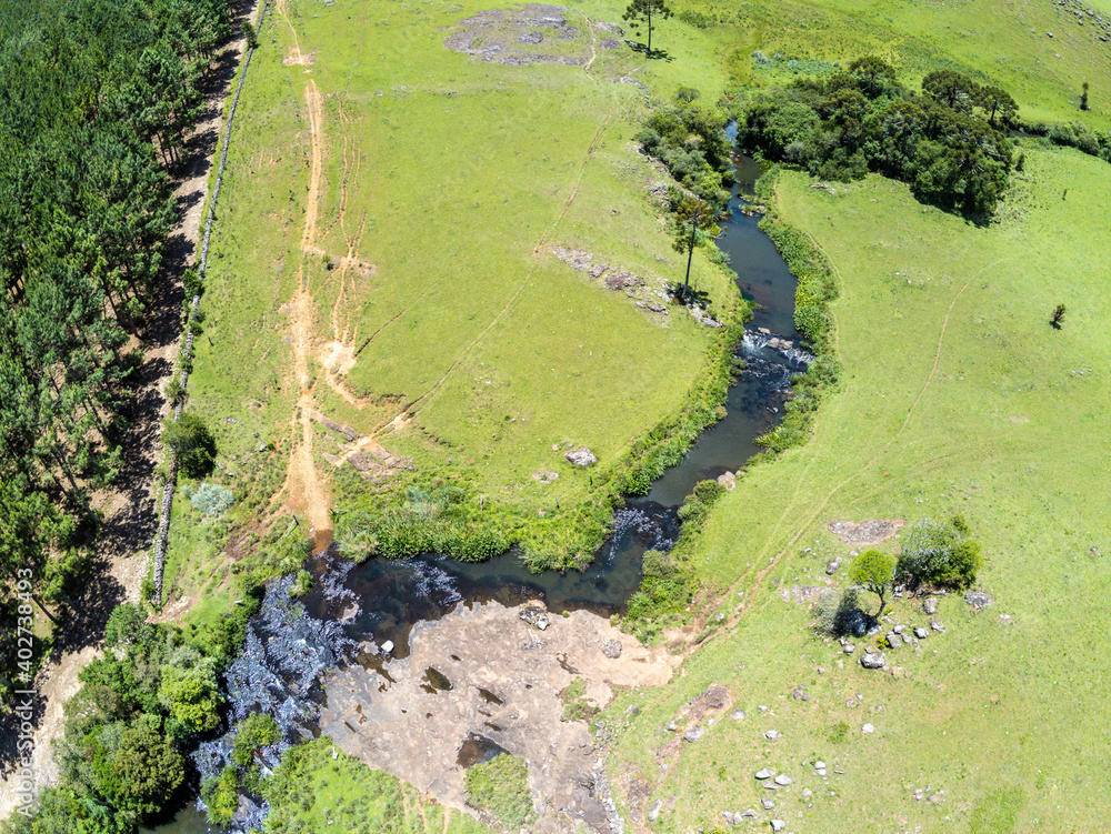 Aerial view of Farm field, forest and stream with waterfall