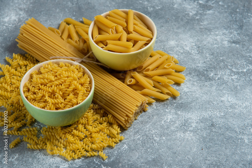 Different types of raw macaroni on a marble background