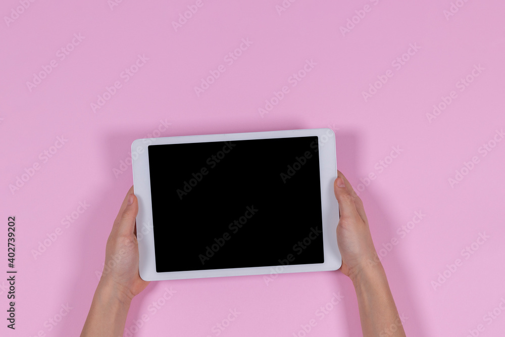 Kid hands holding digital tablet computer on pastel pink background. Top view Kid hands holding digital tablet computer on pastel pink background. Top view