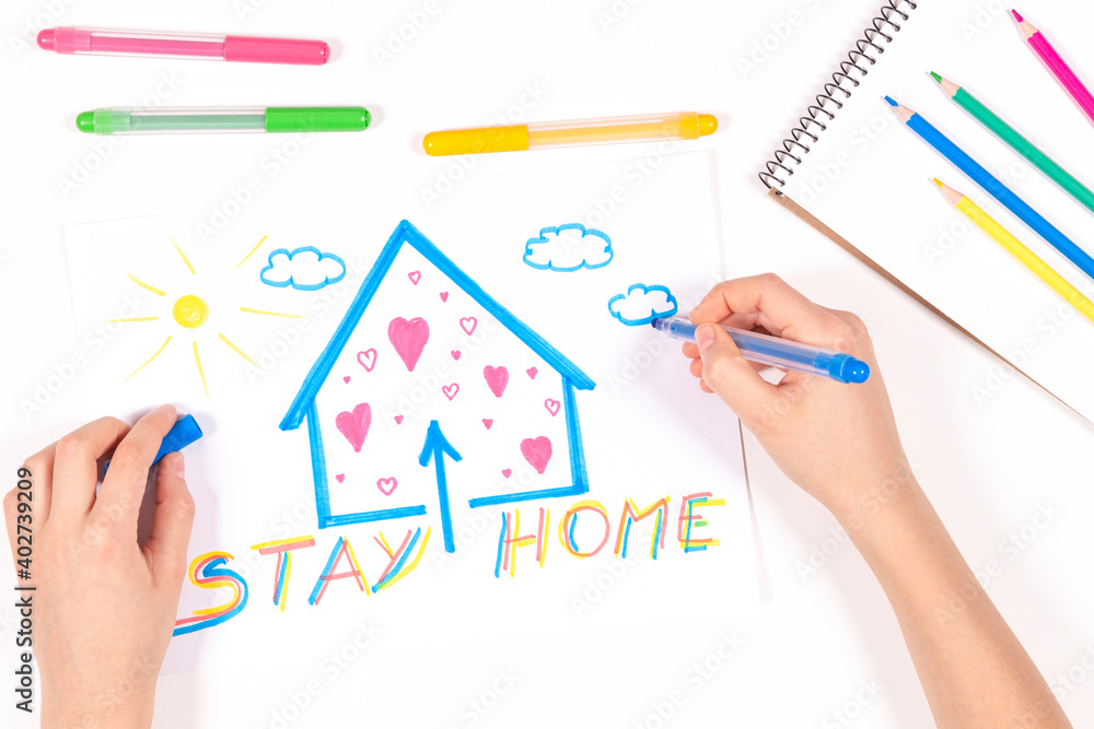 Stay at home. Kid hands drawing picture with house and message Stay home. Top view. Quarantine during coronavirus pandemic Stay at home. Kid hands drawing picture with house and message Stay home. Top view. Quarantine during coronavirus pandemic