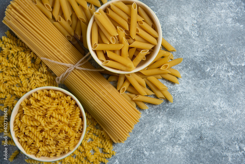 Different types of raw macaroni on a marble background