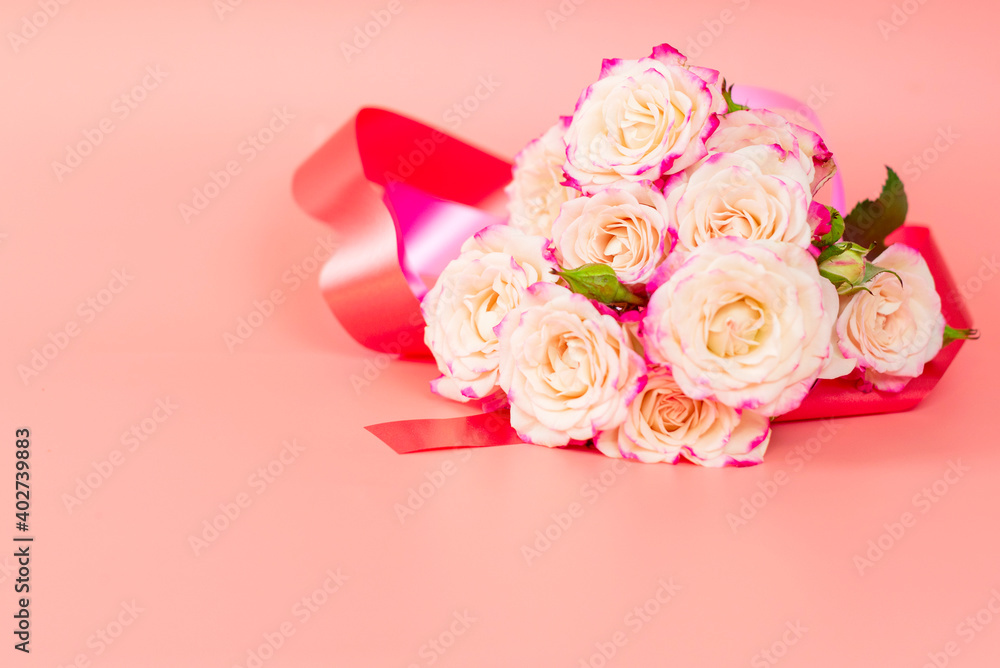 delicate bouquet of bushy peony roses with bright ribbons in the shape of hearts on a pink background, the concept of congratulations on Valentine's day