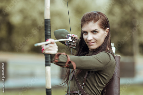 Portrait of young woman archery on forest background, close-up
