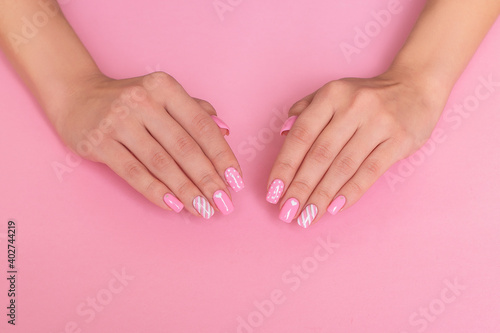 Beautiful female hands with pink manicure nails, hearts and Valentine's day design, with copy space