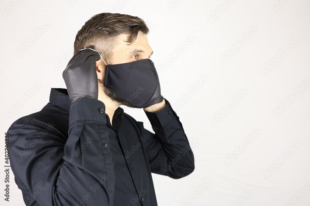 a man wearing black medical gloves wears a protective mask on a white background a man wearing black medical gloves wears a protective mask on a white background