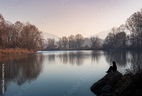 Silhouette of a person sitting on the edge of the river at sunset