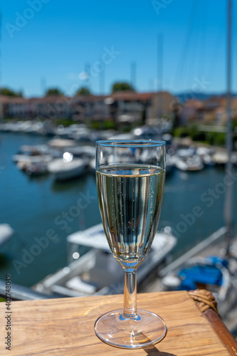 Summer party with sparkling champagne wine and sail boats haven of Port Grimaud on background, Provence, France