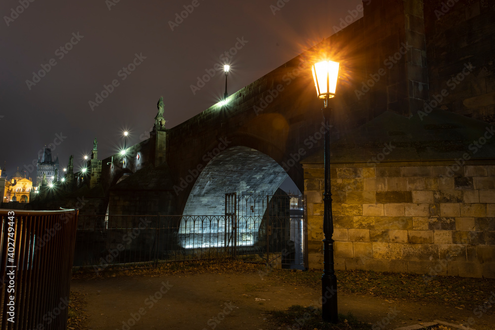 .street light lamp and paving sidewalk with cobblestone and lights in the background on Charles Bridge in the center of Prague at night