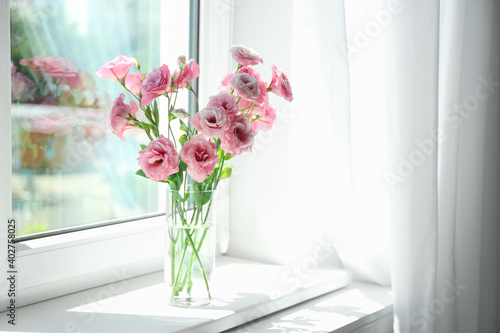 Fototapeta Naklejka Na Ścianę i Meble -  Glass vase with beautiful flowers on window sill in room, space for text