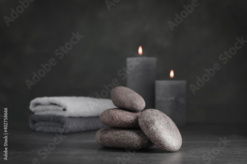 Spa stones with candles and towel on grey table
