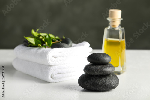 Spa stones, towels and oil on white table