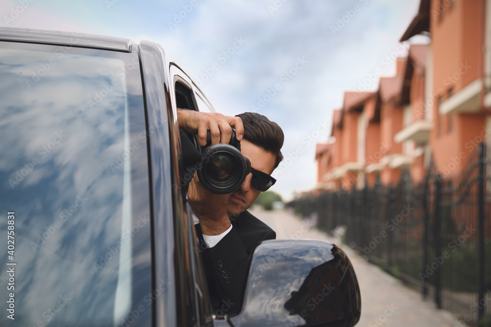 Private detective with camera spying from car Private detective with camera spying from car