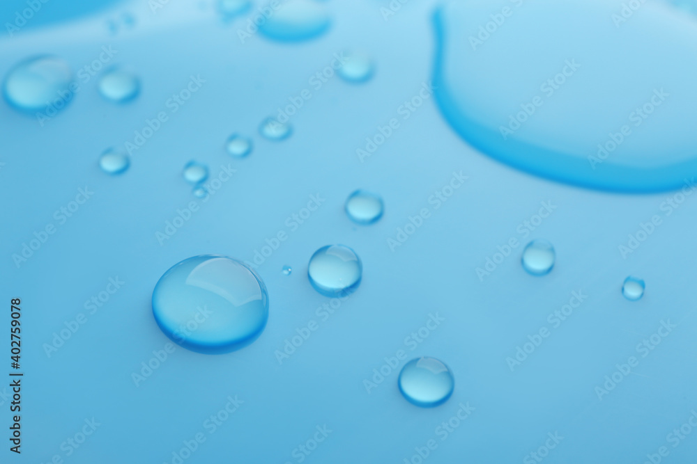Drops of spilled water on light blue background, closeup Drops of spilled water on light blue background, closeup
