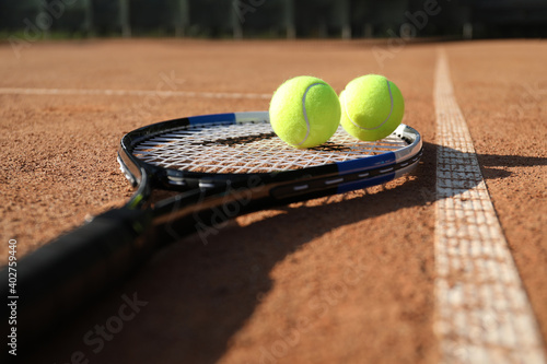 Tennis balls and racket on clay court, closeup © New Africa