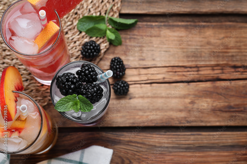 Different delicious lemonades made with soda water on wooden table, flat lay. Space for text Different delicious lemonades made with soda water on wooden table, flat lay. Space for text