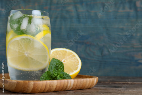 Delicious lemonade made with soda water and fresh ingredients on wooden table against light blue background. Space for text