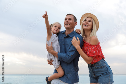 Happy family spending time together near sea on sunny summer day
