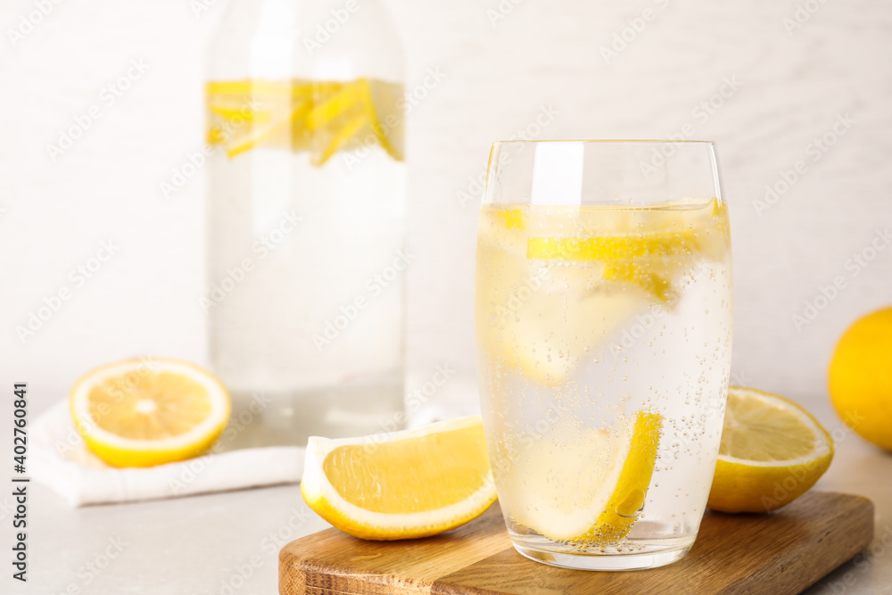 Fototapeta premium Soda water with lemon slices on light table. Space for text