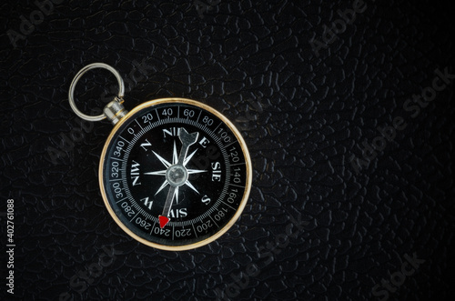  Old compass on black leather background.
