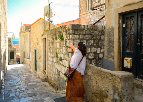 An unidentifiable female tourist takes a photo inside the city walls of Dubrovnik, Croatia.