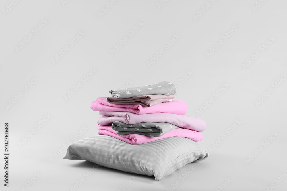 Stack of clean bed sheets and pillow on white background - obrazy, fototapety, plakaty 