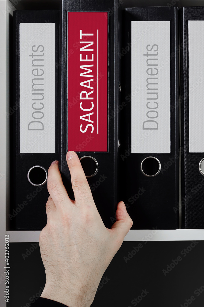 Sacrament. Folder with label on the shelf of a lawyer. Red label with text in focus. Sacrament. Folder with label on the shelf of a lawyer. Red label with text in focus.