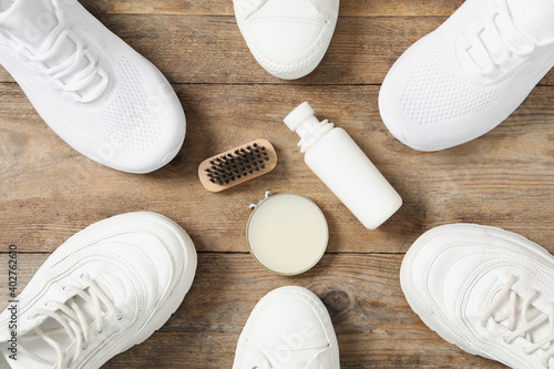 Flat lay composition with stylish footwear and shoe care accessories on wooden background