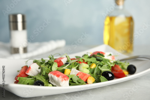 Tasty crab stick salad served on grey marble table, closeup