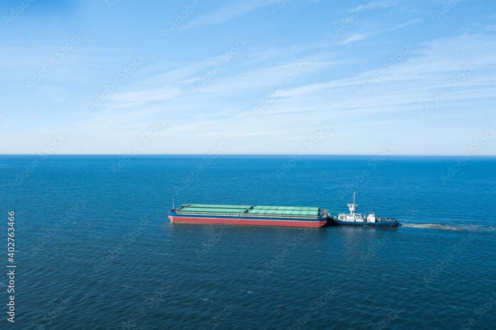 Tugboat pulling barge with cargo by water, aerial view Tugboat pulling barge with cargo by water, aerial view