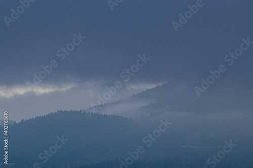forest-covered mountain range covered under a heavy cloud in the morning 
