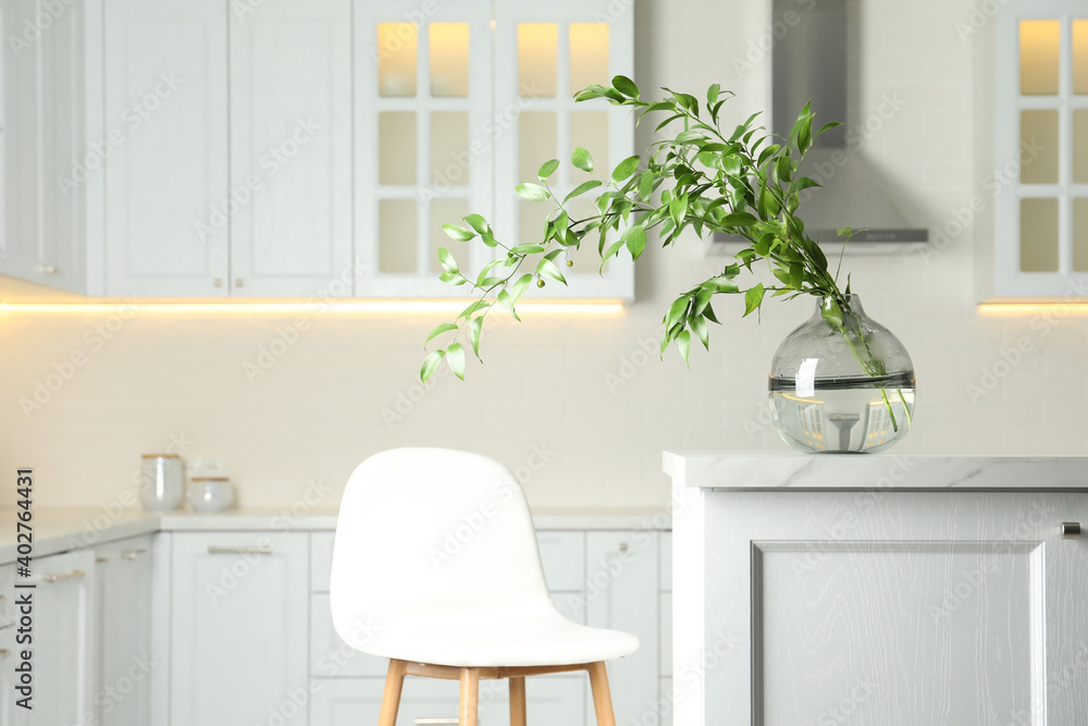 Decorative vase with branch on table in kitchen Decorative vase with branch on table in kitchen