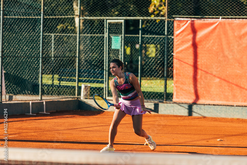 Caucasian woman in sportive outfit playing tennis on a clay court