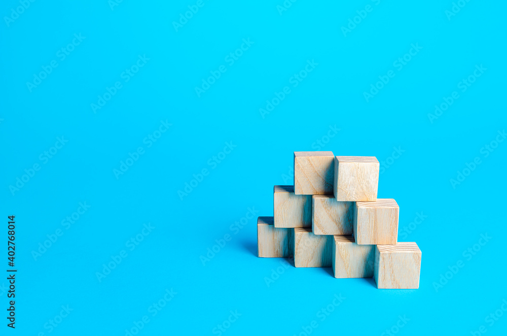Wooden blocks pyramid on a blue background. Slide for presentation. Copy space, place for text. Steps. Minimalism. Simple shapes geometry. Wooden blocks pyramid on a blue background. Slide for presentation. Copy space, place for text. Steps. Minimalism. Simple shapes geometry.
