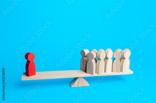 The red human figurine has equal weight against a group of people. Leader and valued employee. Highly qualified specialist. Inequality of rights. Social significance. Steadfastness and self-confidence photo